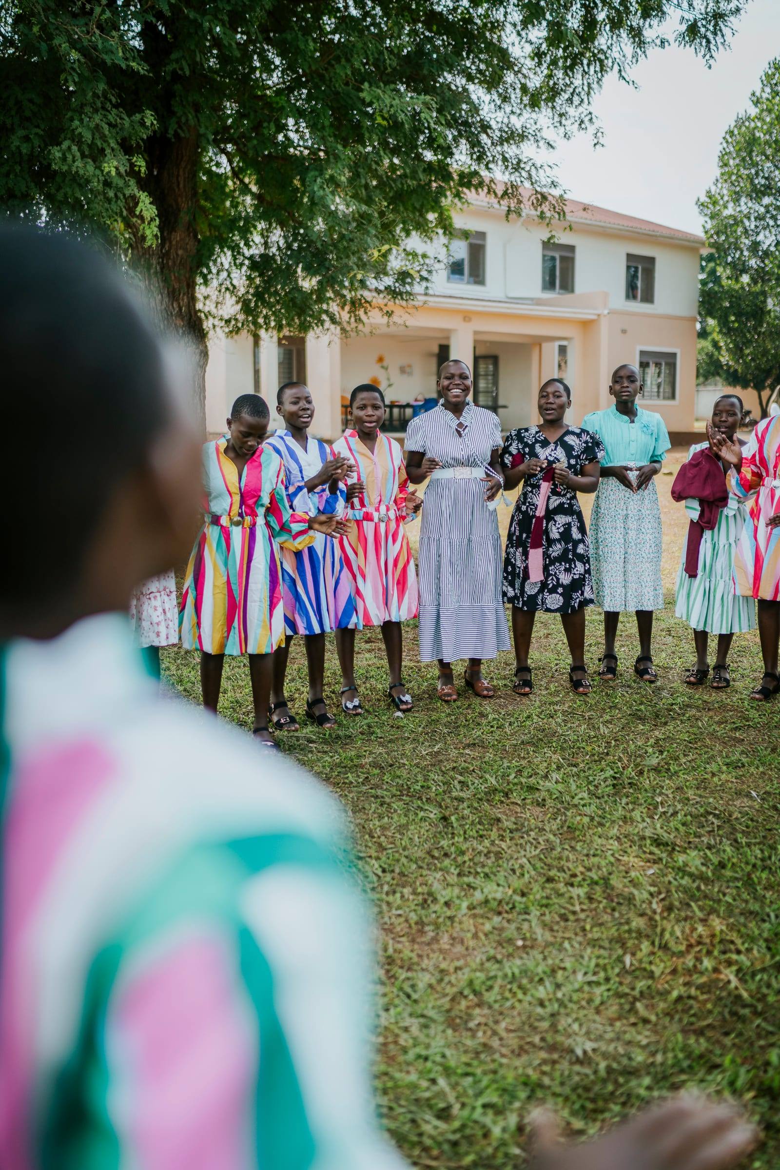 Women in bright dresses gather together outside a school
