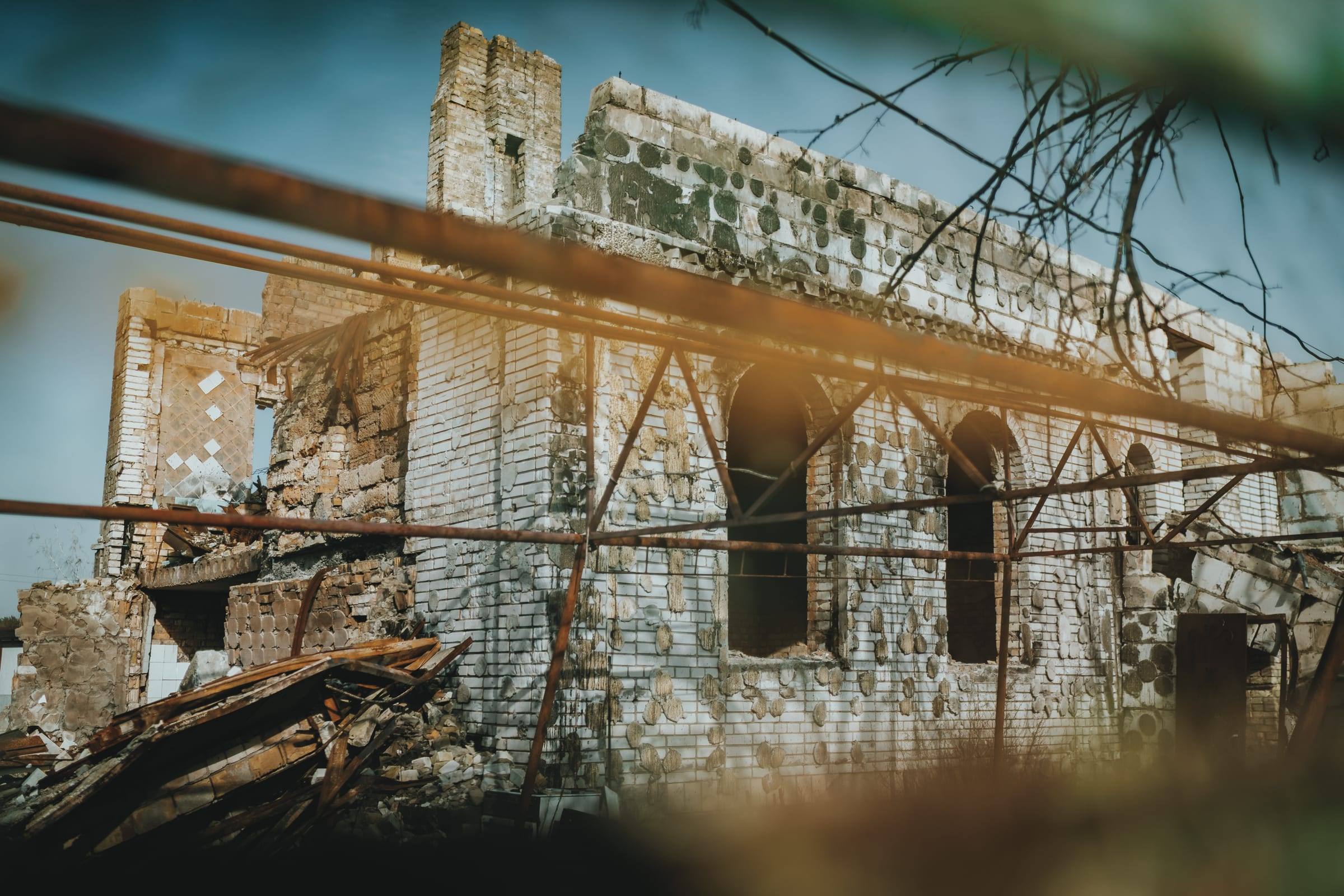 A house damaged in the war stands roofless behind bare trees