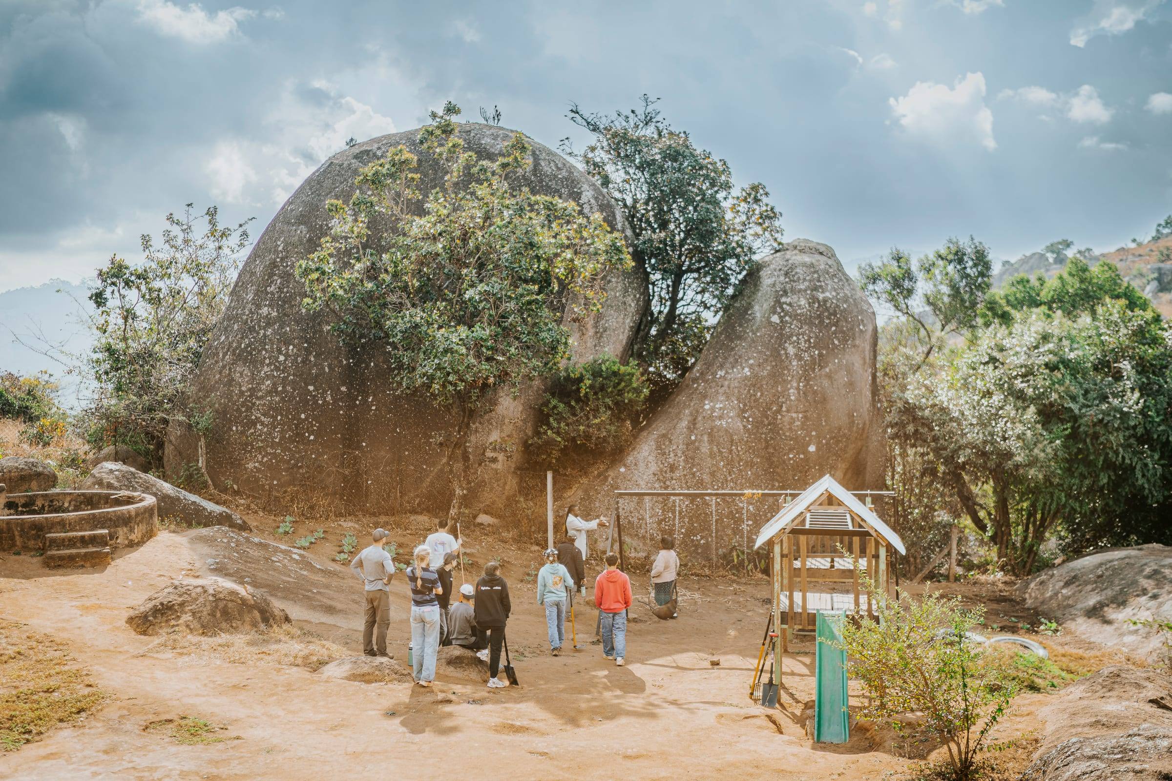A team walks toward giant granite boulders under a wide sky