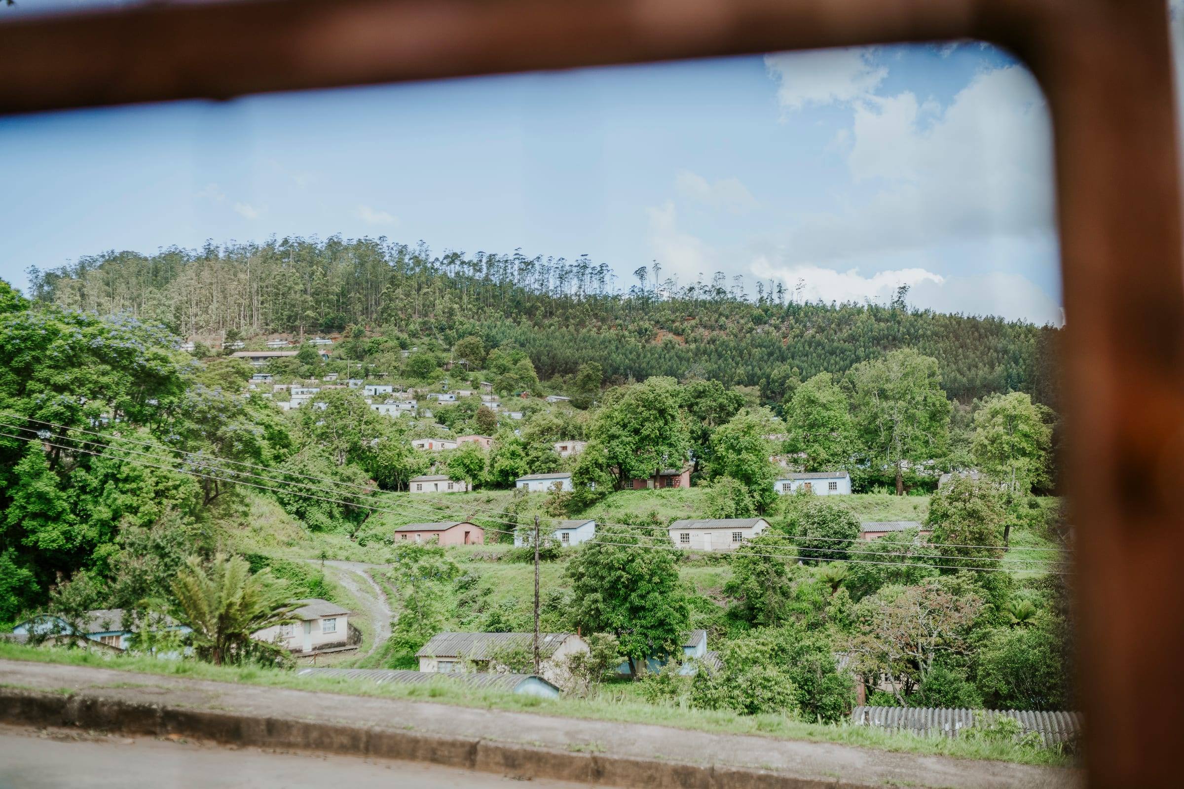 A green valley of homes seen through an open window frame