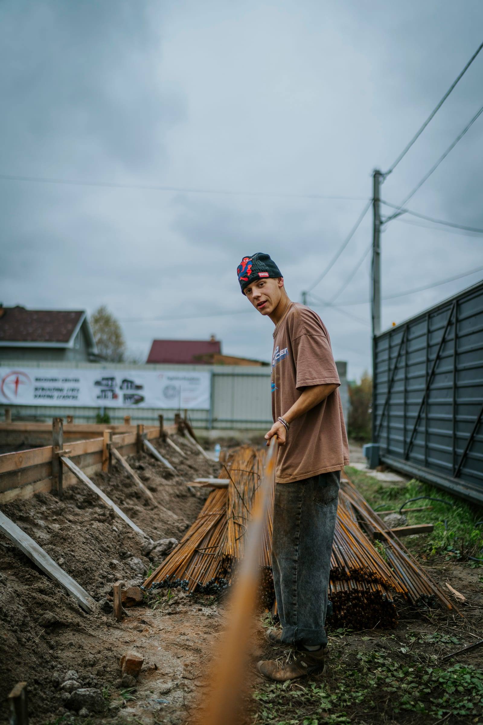 A young volunteer works beside a bundle of rebar at a building site