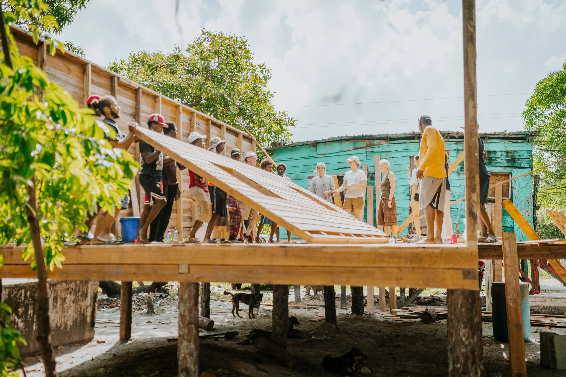 A team raises a wall frame on the deck of a new stilt home